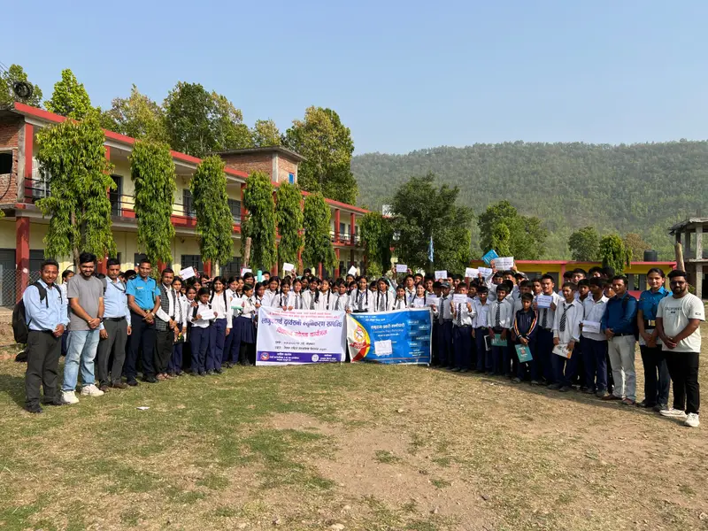 Students, teachers and volunteers standing together outside a school during an awareness programme in Dang.